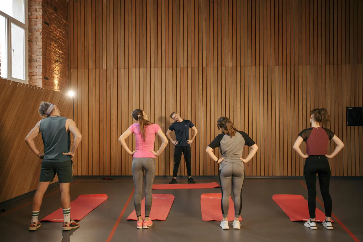 Personal trainer leading group fitness class with movement coaching