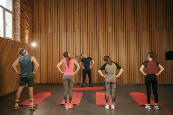 Personal trainer leading group fitness class with movement coaching